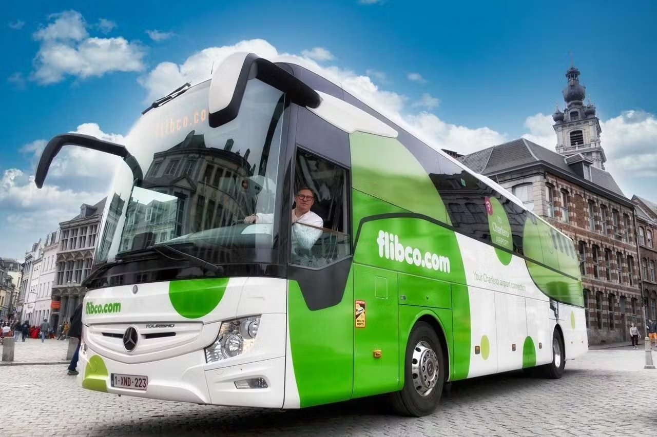 Un bus Flibco vert et moderne garé dans un cadre urbain central à Rome, représentant l'arrivée du service de navette de l'aéroport de Fiumicino à la ville – parfait pour les voyageurs à la recherche d'un transfert aéroport direct et confortable